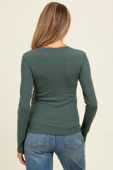 woman wearing a green long sleeve maternity top, viewed from the back, paired with blue jeans