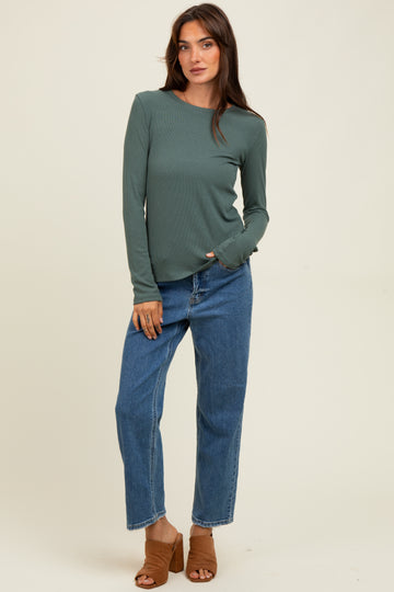 woman wearing a long sleeve green top and high-waisted blue jeans with brown mules