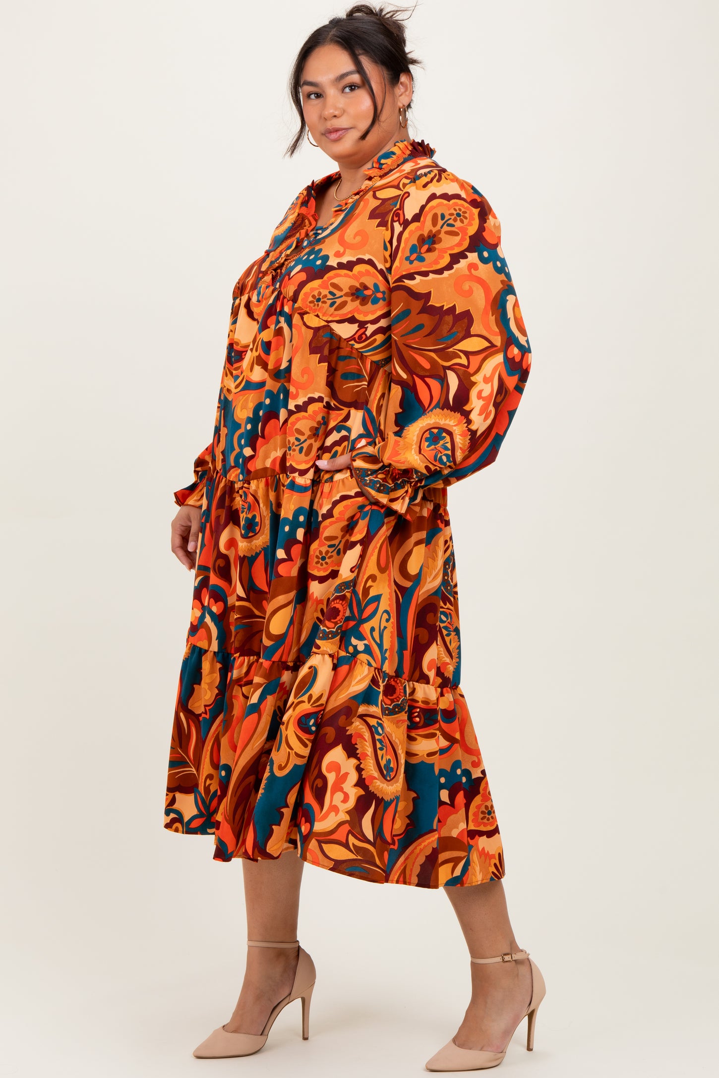 woman wearing a colorful patterned plus-size midi dress with long sleeves and a ruffled hemline