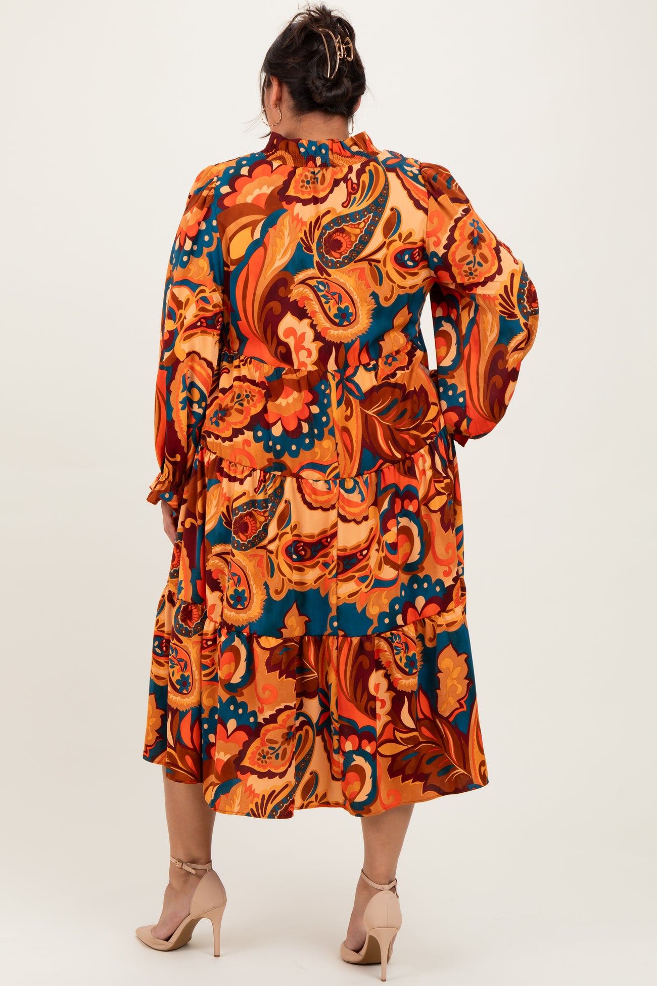 woman wearing a back view of a colorful floral printed plus size midi dress with long sleeves and tiered skirt