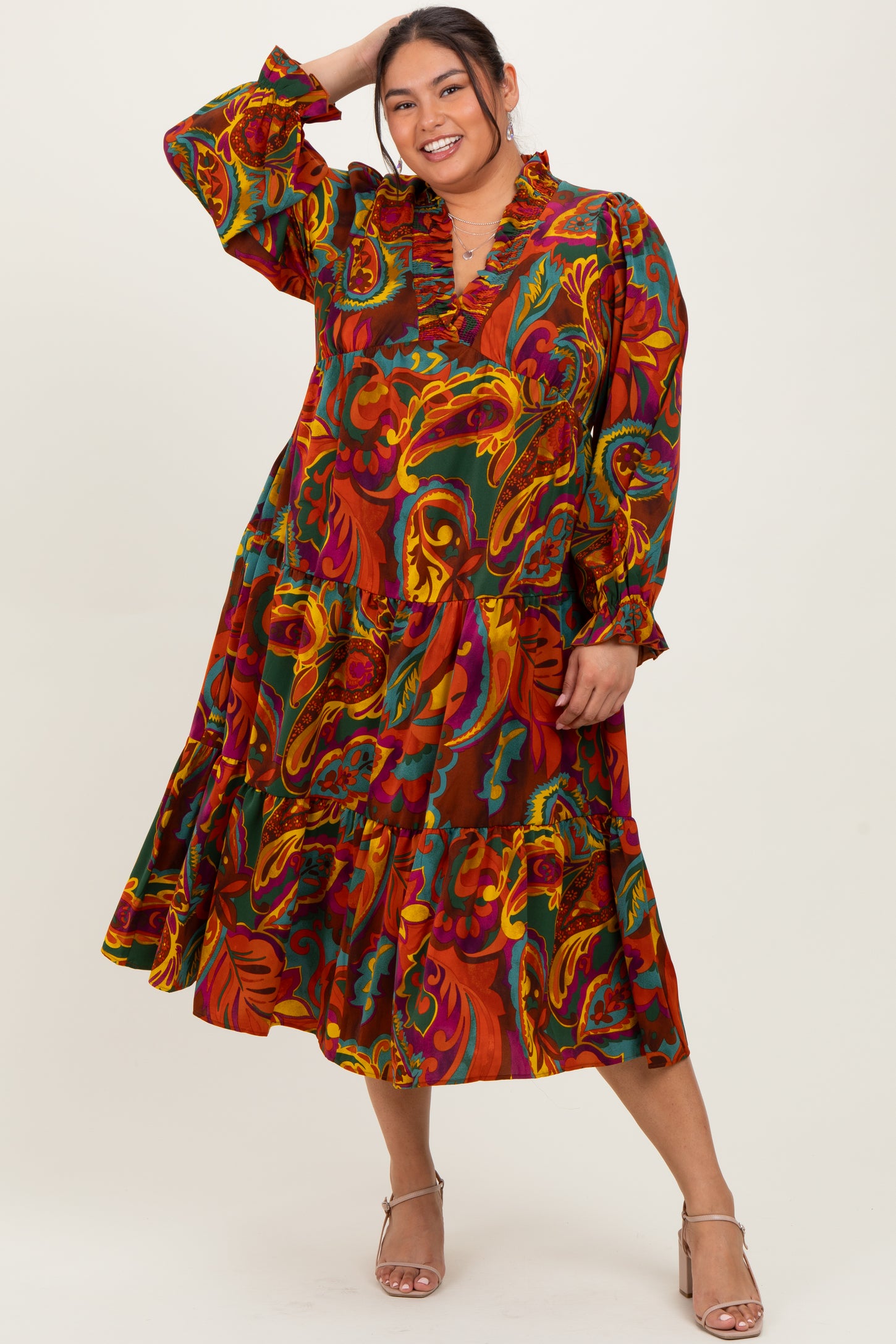 woman wearing a colorful paisley print long sleeve plus size dress with a ruffled neckline and tiered skirt