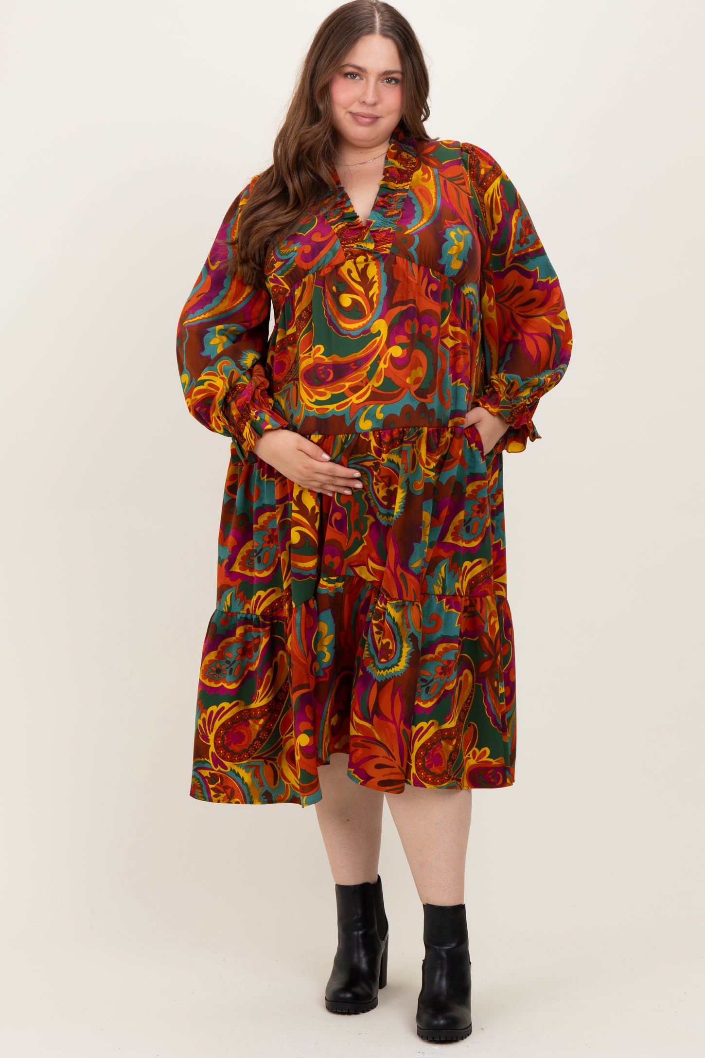 woman wearing a colorful paisley print maternity dress with a v-neck and tiered skirt, holding her baby bump