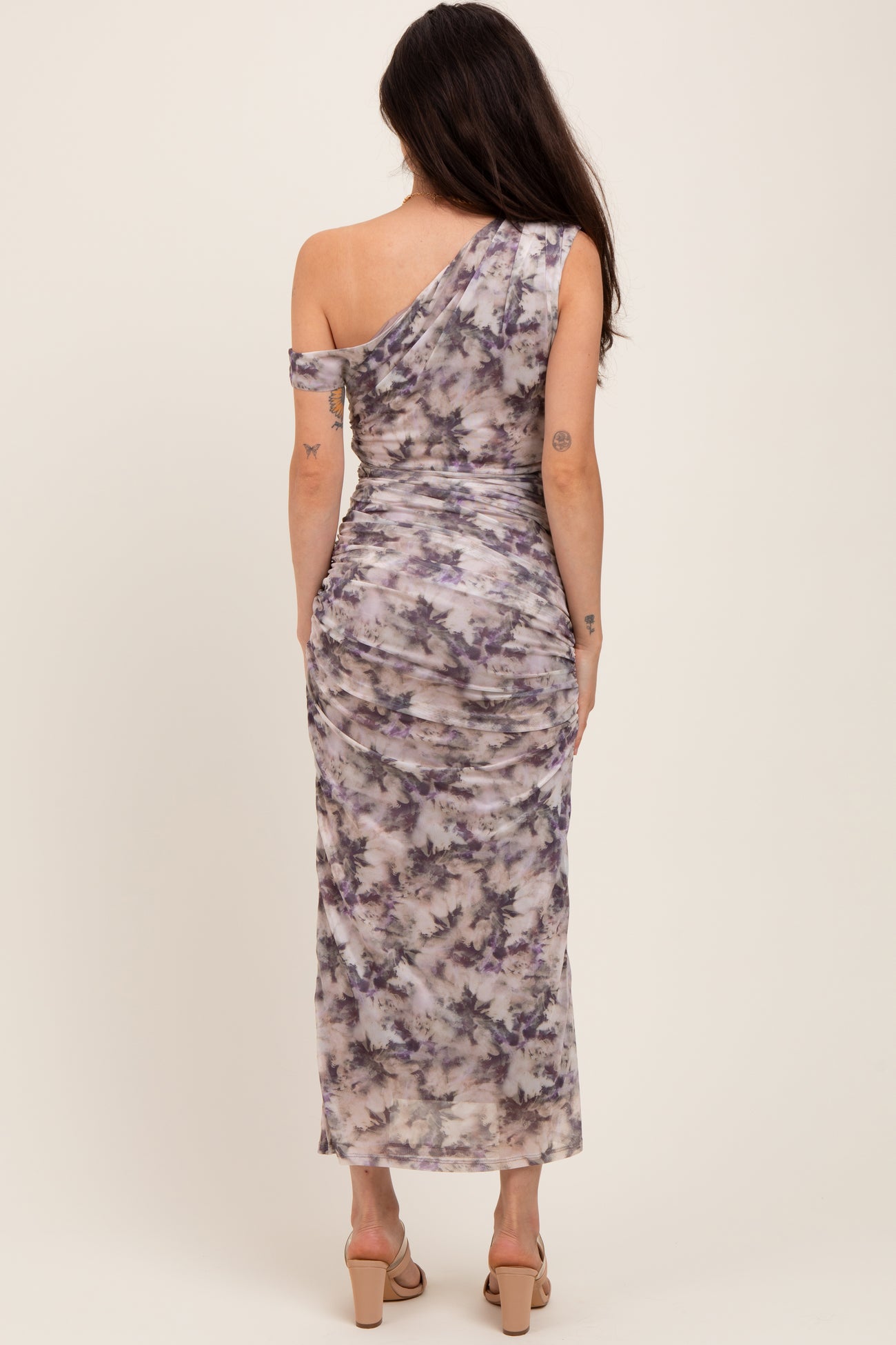 woman wearing a one-shoulder purple and gray tie-dye maternity dress with a fitted silhouette