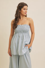 woman wearing a light blue strapless smocked top with a relaxed fit and side pockets