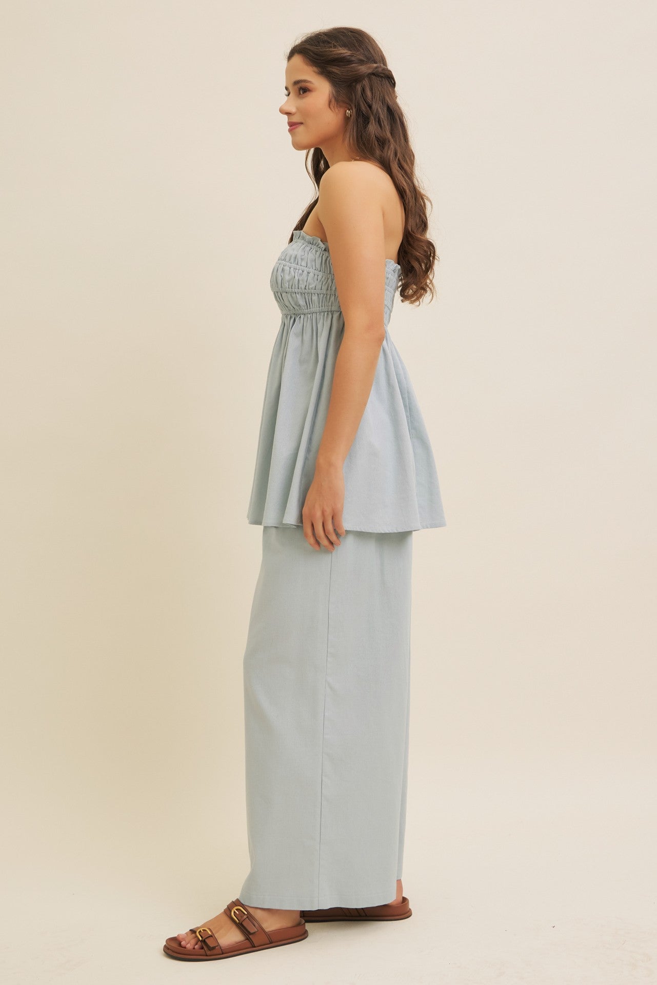 woman wearing a light blue smocked peplum top paired with matching wide-leg pants and brown slide sandals