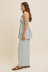 woman wearing a light blue smocked peplum top paired with matching wide-leg pants and brown slide sandals
