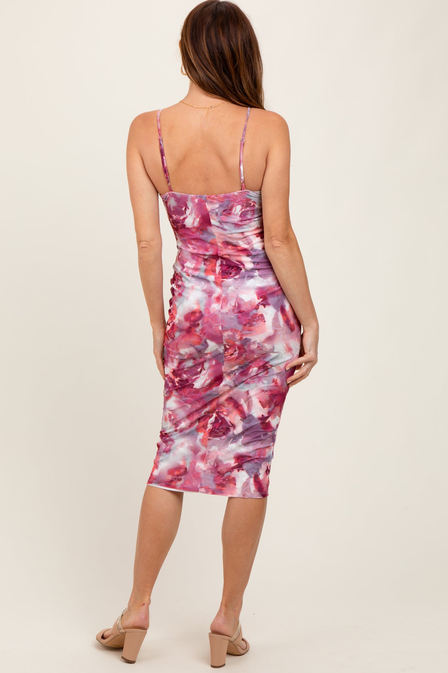 woman wearing a floral print midi dress in shades of pink and purple, showing the back view
