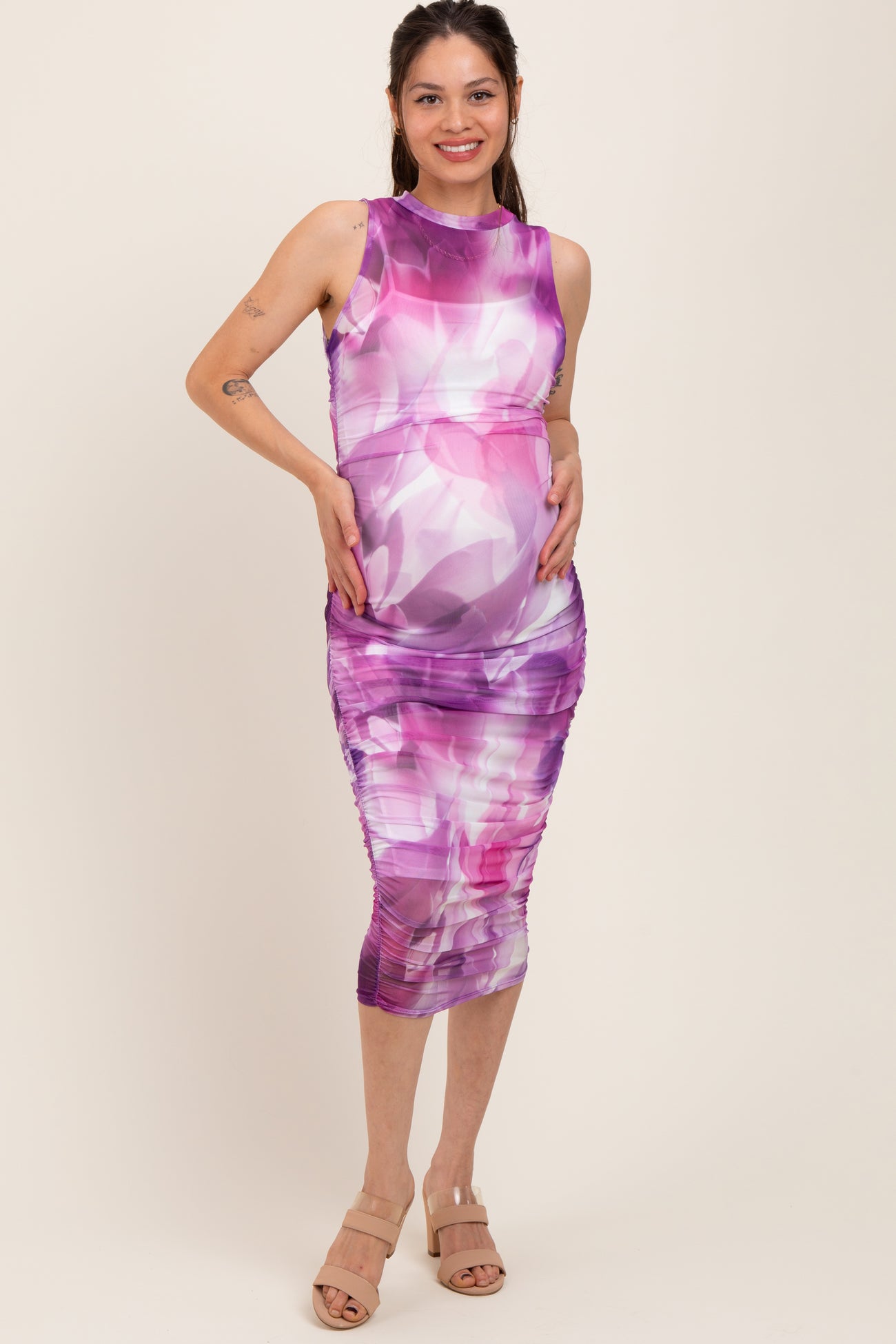 woman wearing a purple floral print maternity dress with ruching and a visible baby bump