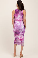 woman wearing a purple and pink floral print maternity dress with gathered details, showing her baby bump from the back