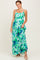 woman wearing a green and blue leaf print maxi dress with adjustable straps and flowy silhouette