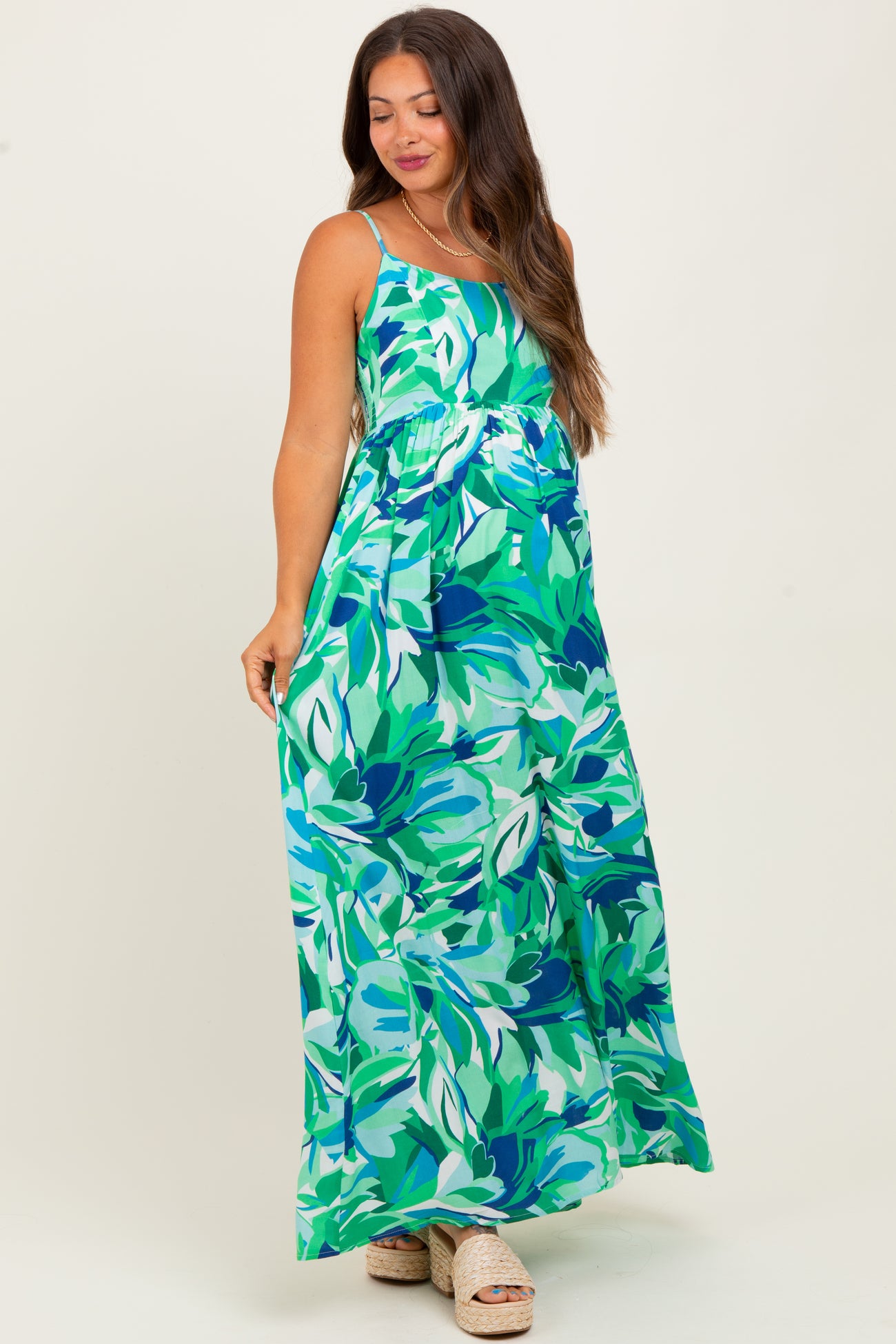 woman wearing a green floral maxi dress, showcasing her baby bump, in a maternity style