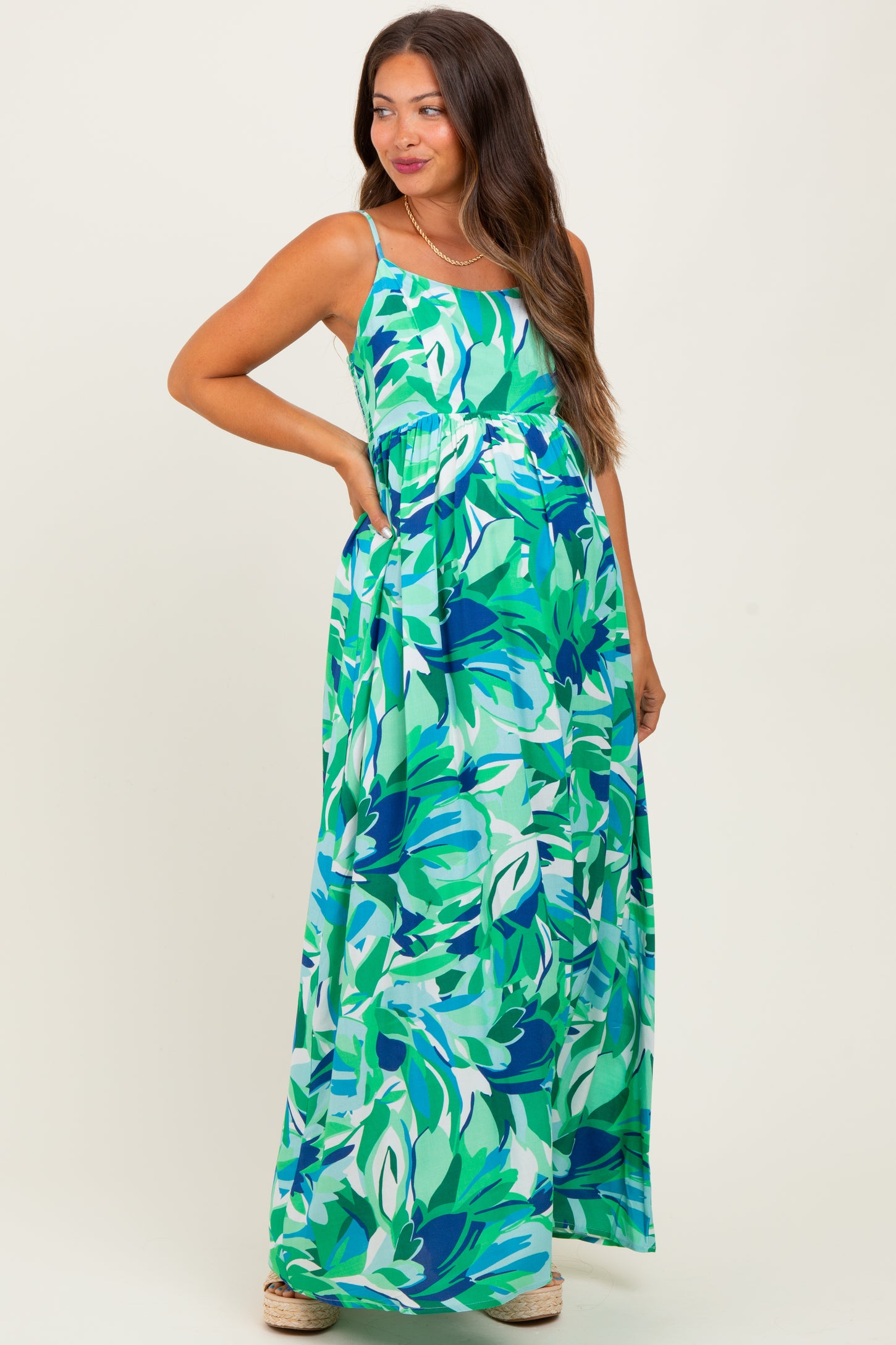 woman wearing a colorful floral maternity maxi dress with a relaxed fit and a gathered waistband, showcasing her baby bump