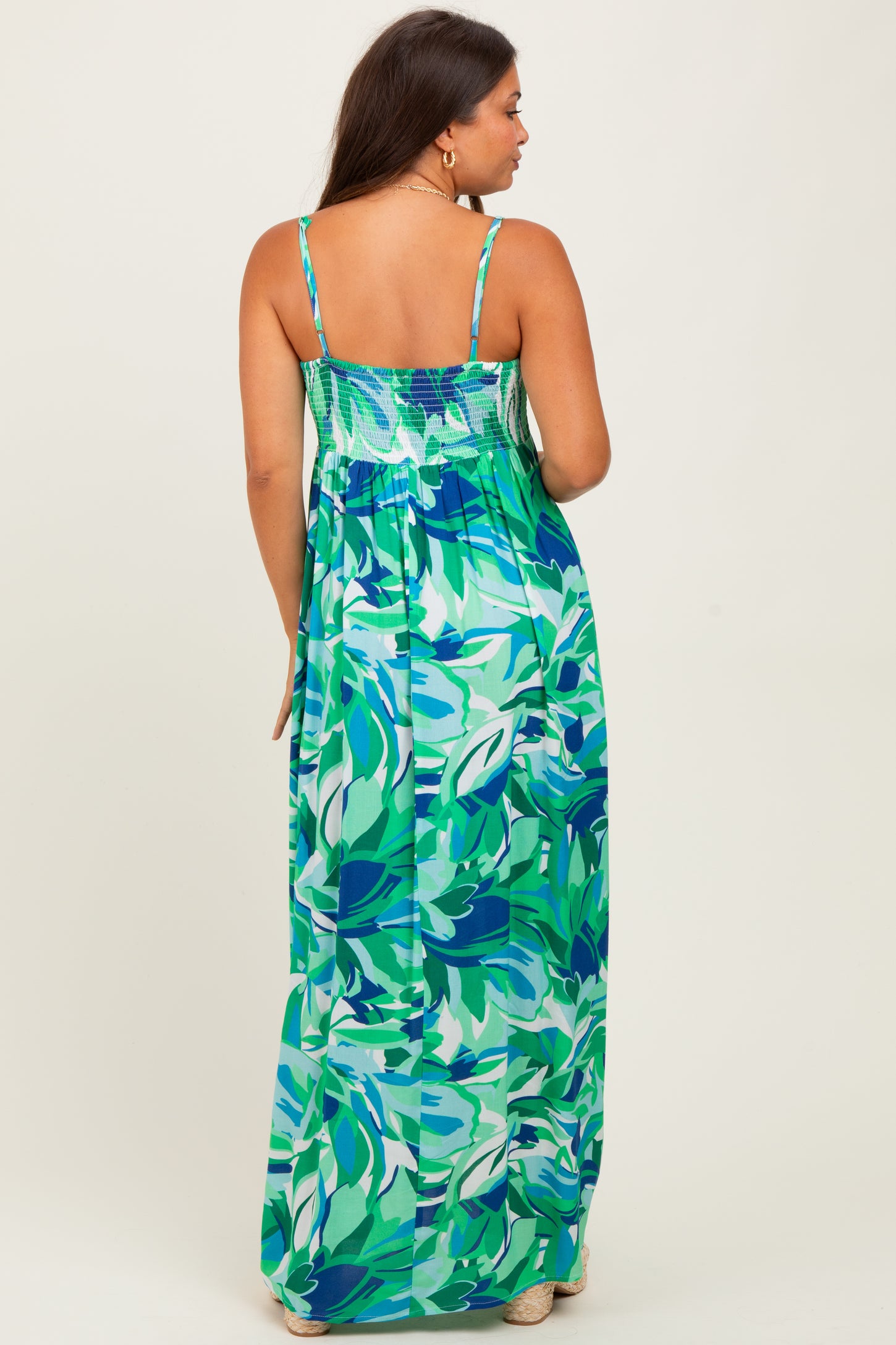 woman wearing a colorful floral print maternity maxi dress with adjustable straps and a smocked back