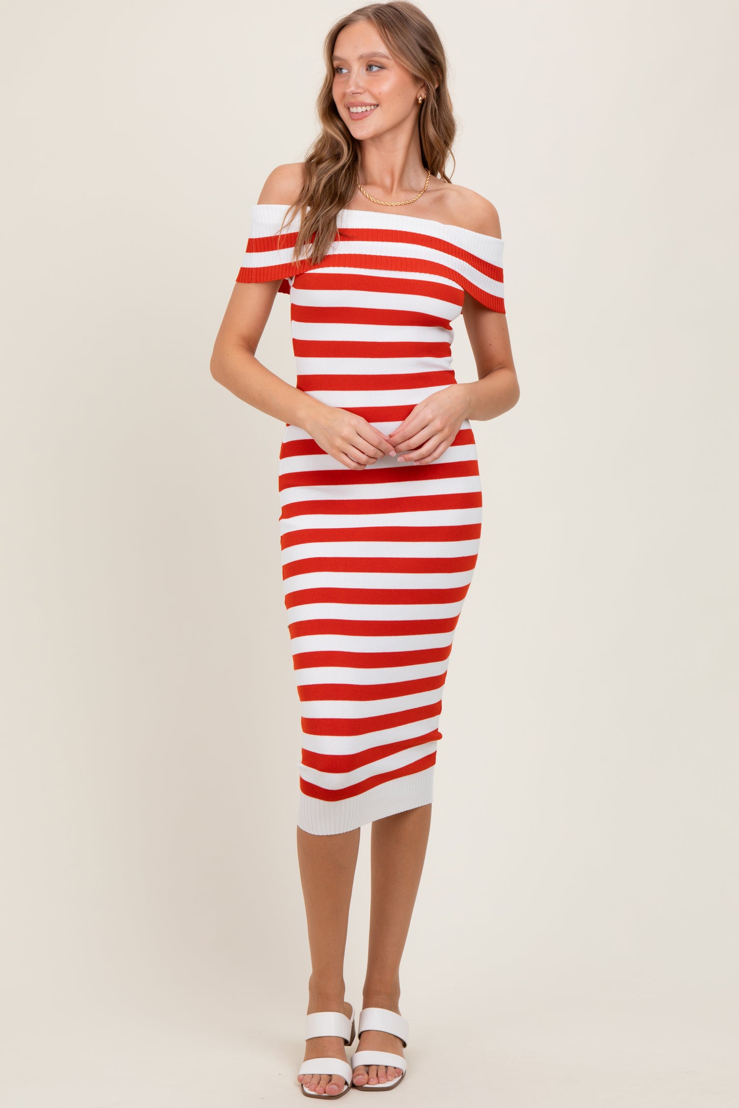 woman wearing a red and white striped off-the-shoulder midi dress with a fitted silhouette and white heels