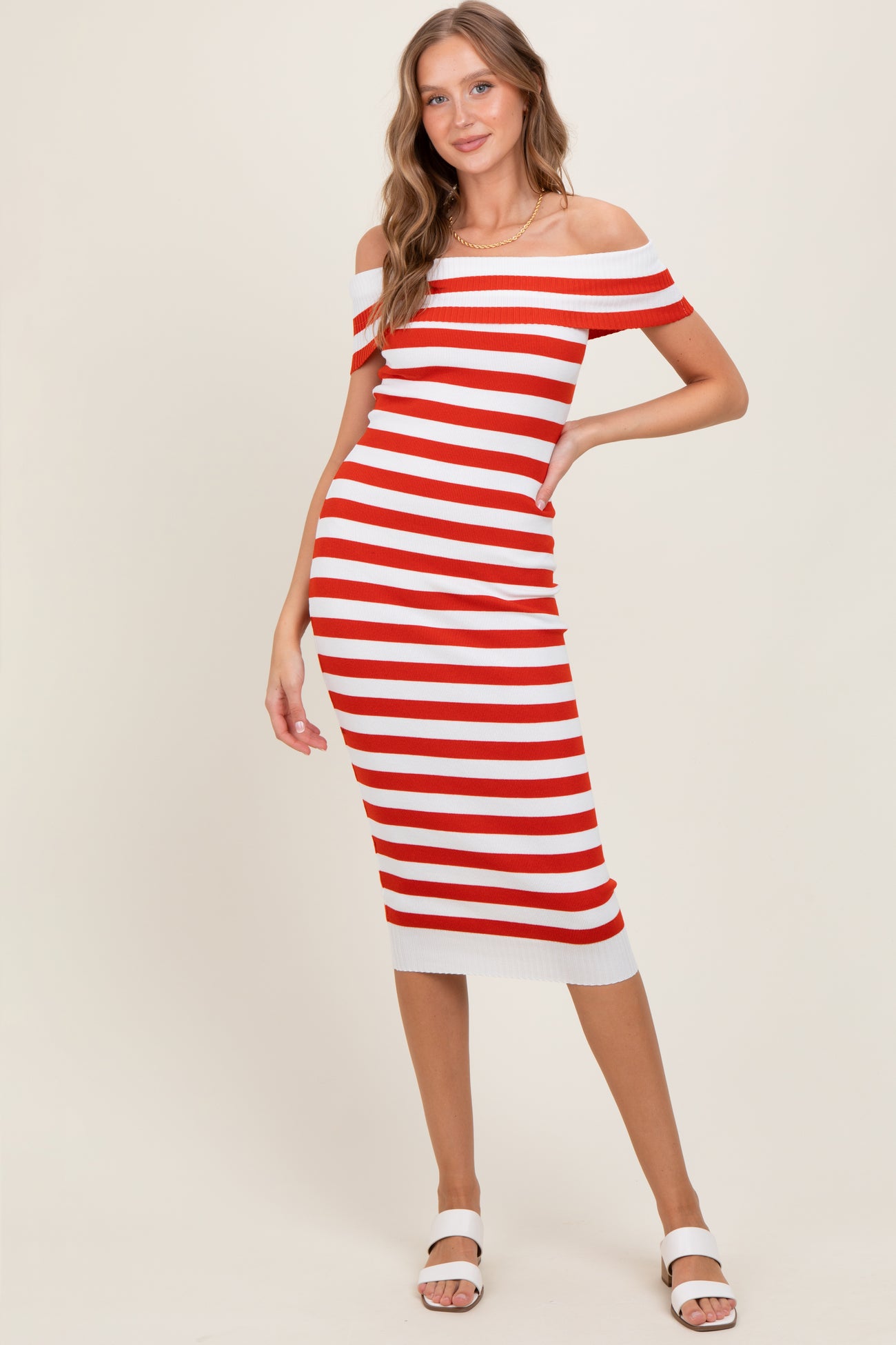 woman wearing a red and white striped off-the-shoulder midi dress with a fitted silhouette and white heeled sandals