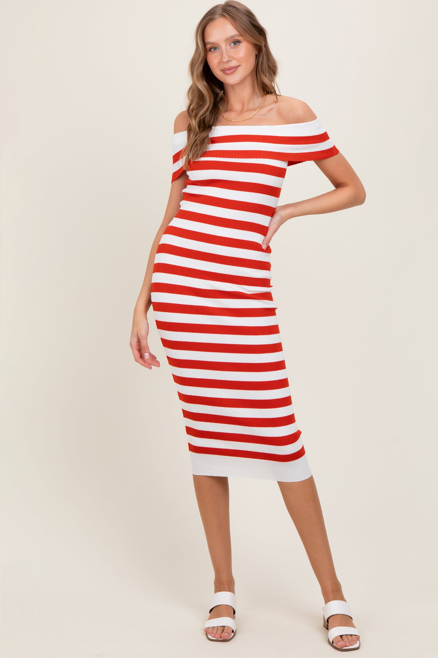 woman wearing a red and white striped off-the-shoulder midi dress with a fitted silhouette and white heeled sandals