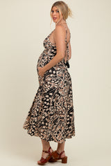 woman wearing a black and pink patterned maternity dress with spaghetti straps and holding her baby bump