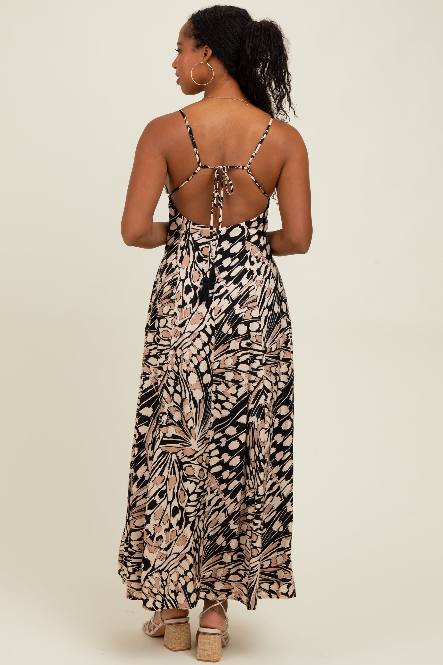 woman wearing a black and cream floral maxi dress with a tie back and a flowy skirt
