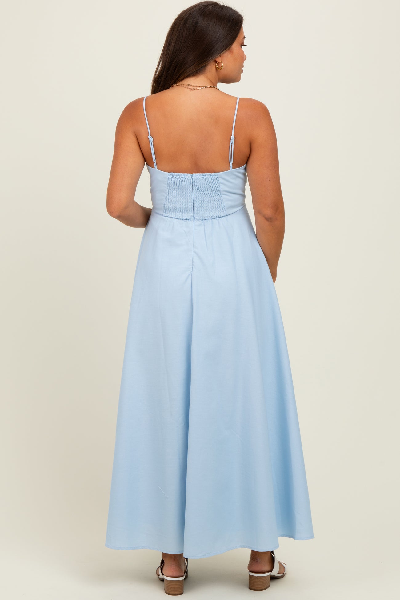 woman wearing a light blue maternity maxi dress with a smocked back, showing off her baby bump