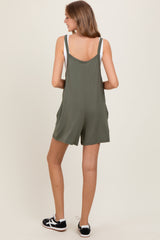 woman wearing a back view of an olive green sleeveless romper with adjustable straps and side pockets