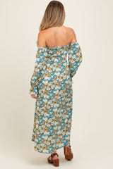 woman wearing a floral off-the-shoulder maternity dress with long sleeves and a flowing skirt, revealing a baby bump