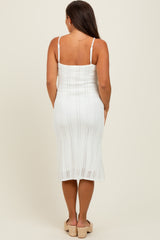 woman wearing a white crochet maternity dress with a fitted bodice and midi length, showing off a baby bump from behind