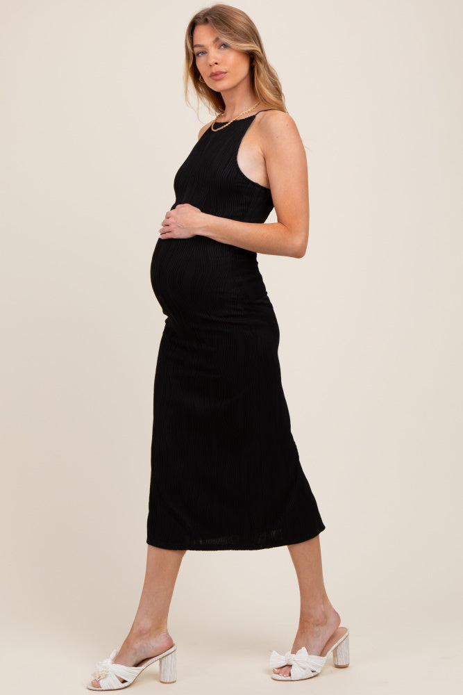 woman wearing a black ribbed maternity dress and showing her baby bump, styled with white heeled slides