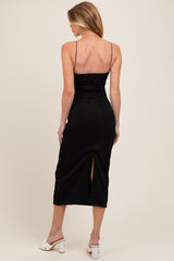 woman wearing a black maternity midi dress with a ribbed texture and a back slit, showing off her baby bump