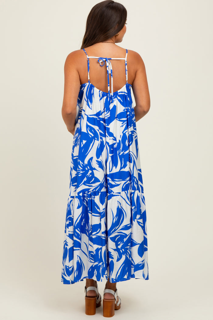 woman wearing a blue and white floral maternity maxi dress with a tie back and flowy skirt