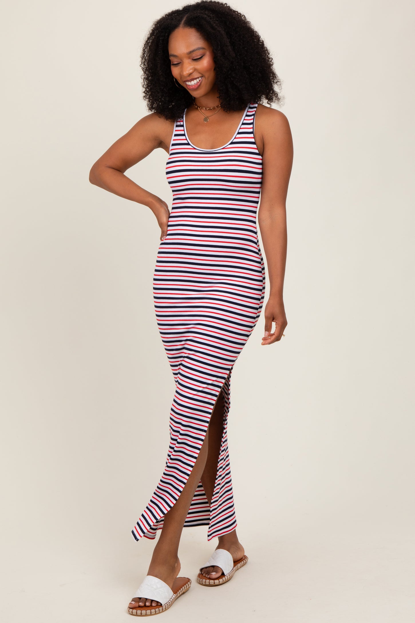 woman wearing a navy and white striped maxi dress with a thigh-high slit and smiling while walking