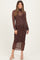 woman wearing a brown polka dot long sleeve maternity dress with a fitted silhouette and holding her baby bump