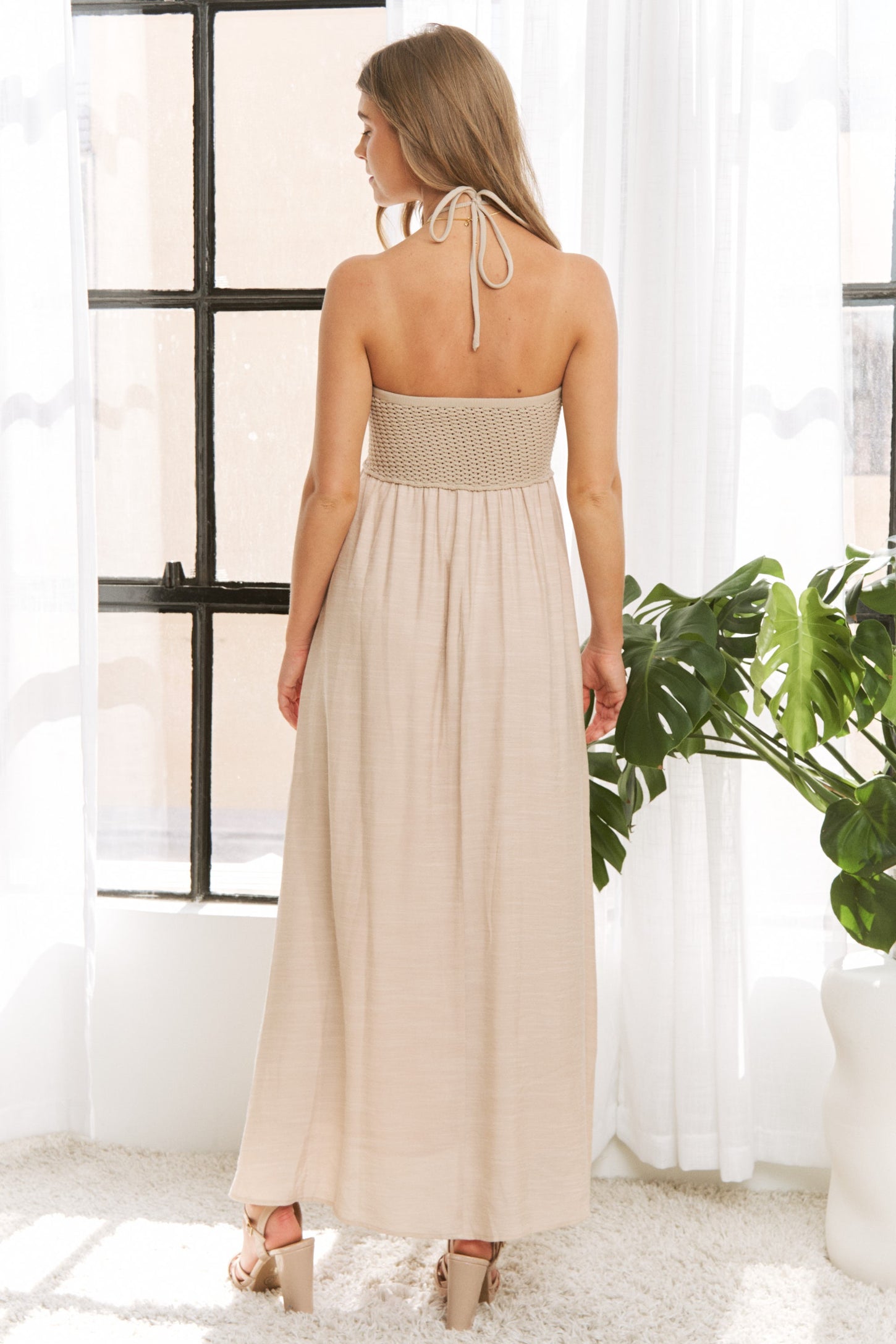 woman wearing a backless beige maxi dress with a smocked bodice and adjustable tie straps