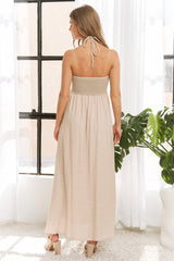 woman wearing a backless beige maxi dress with a smocked bodice and adjustable tie straps