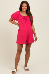 woman wearing a bright pink short maternity romper with a tie neckline and puff sleeves, showcasing her baby bump