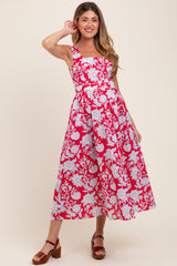 woman wearing a pink and white floral print maternity dress with a fitted bodice and flared skirt