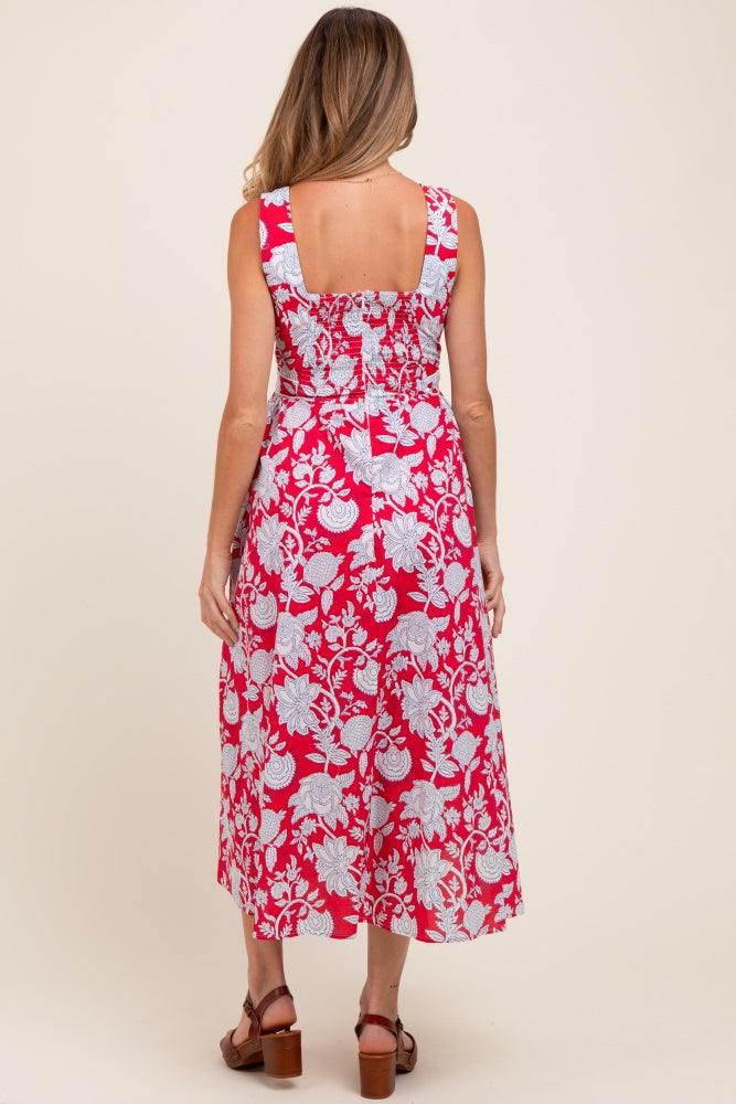 woman wearing a red floral maternity maxi dress, showing the back detail and a fitted bodice design