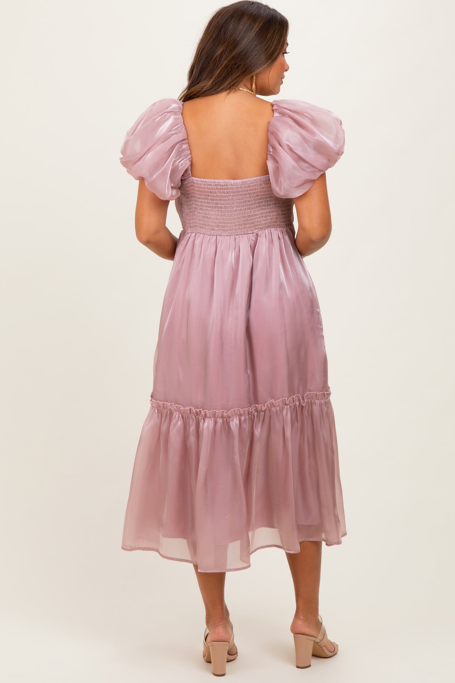 woman wearing a pink puff sleeve maternity dress with a smocked bodice and tiered skirt, showing a baby bump