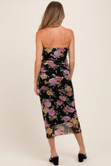 woman wearing a black floral print strapless maternity dress with a fitted silhouette and mid-length cut