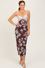woman wearing a brown floral midi dress with a sheer bodice and spaghetti straps, standing in a neutral background