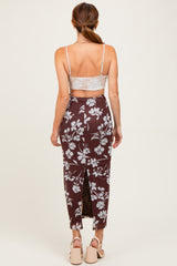 woman wearing a brown floral skirt with a high slit and a light gray crop top, seen from the back