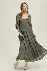 woman wearing a dark green maxi dress with ruffle details and puff sleeves, paired with white ankle boots