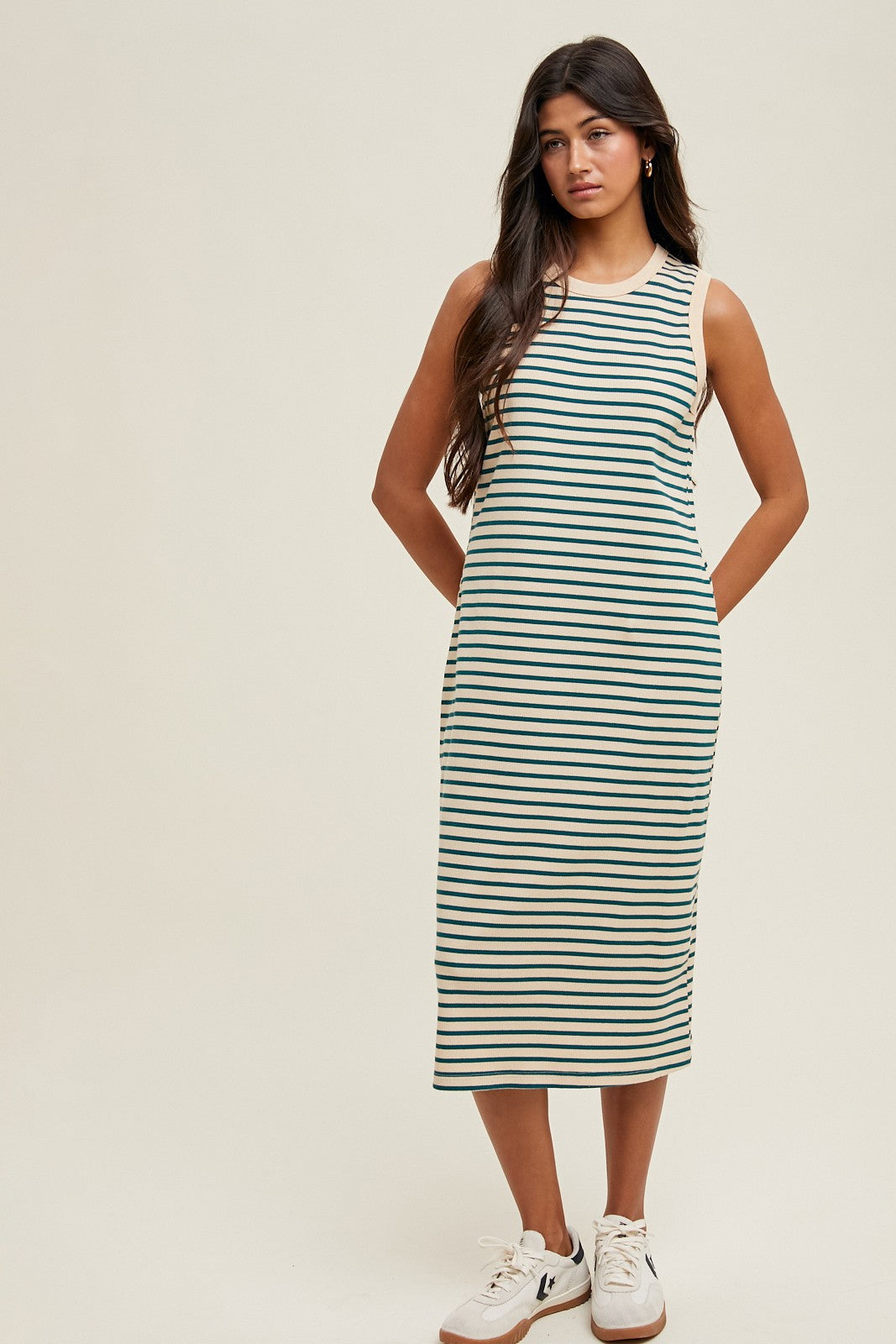 woman wearing a striped sleeveless midi dress with side pockets and white sneakers