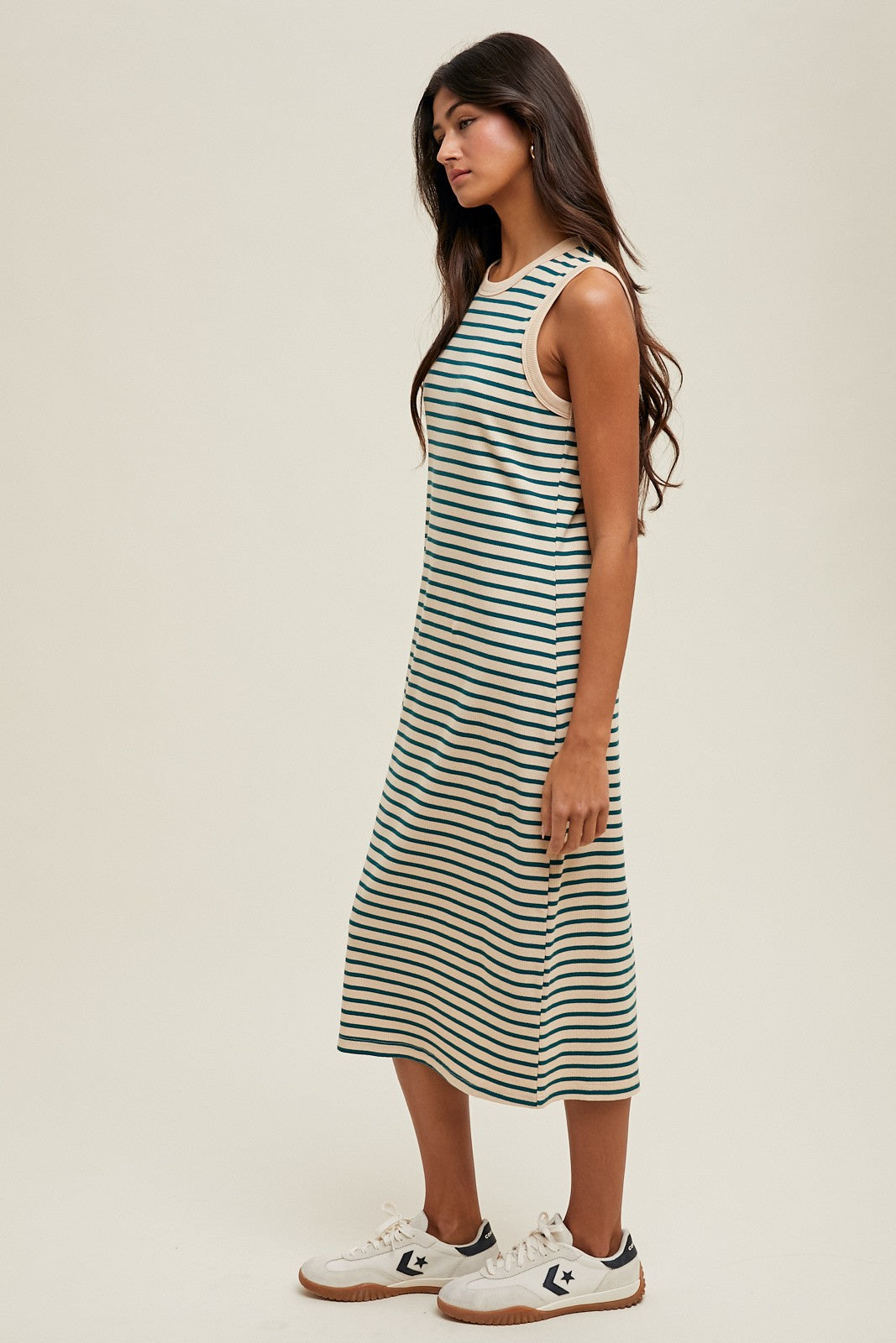 woman wearing a striped sleeveless midi dress in green and white with a relaxed fit and side slit