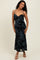 woman wearing a black floral slip dress with spaghetti straps and a fitted silhouette, posing with a smile