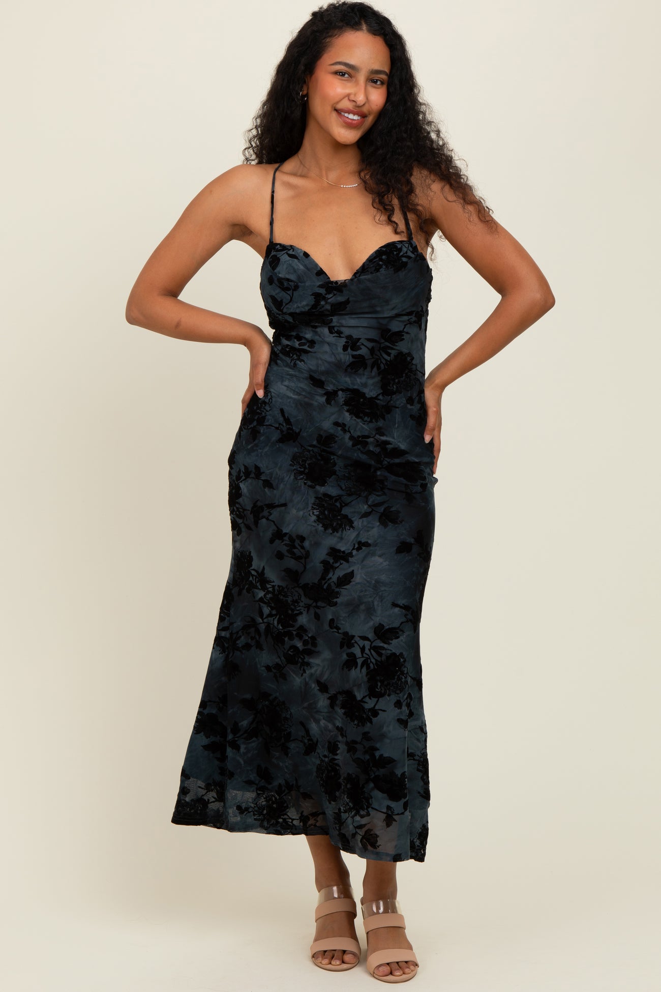 woman wearing a black floral print maxi dress with spaghetti straps and a fitted bodice