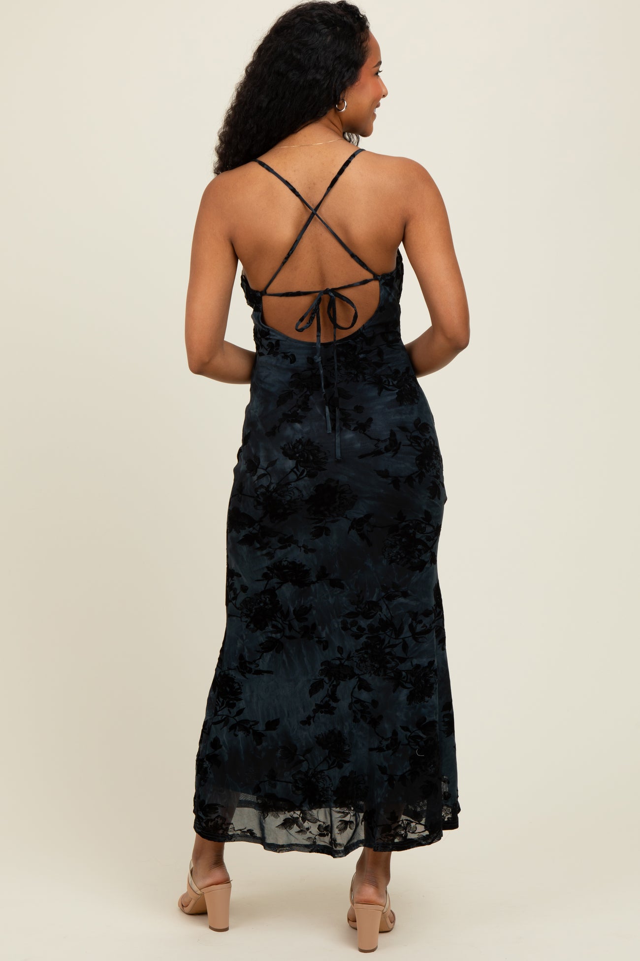 woman wearing a black floral maxi dress with a crisscross back detailing, showing a flowy silhouette