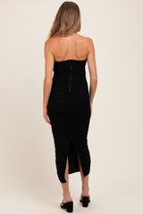 woman wearing a black strapless ruched maternity dress with a back zip and side slit