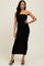 woman wearing a black strapless ruched midi dress with side slit and black heels