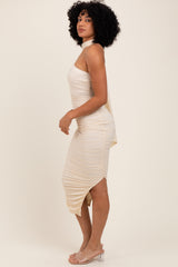 woman wearing a cream asymmetrical bodycon dress with ruching and a halter neckline