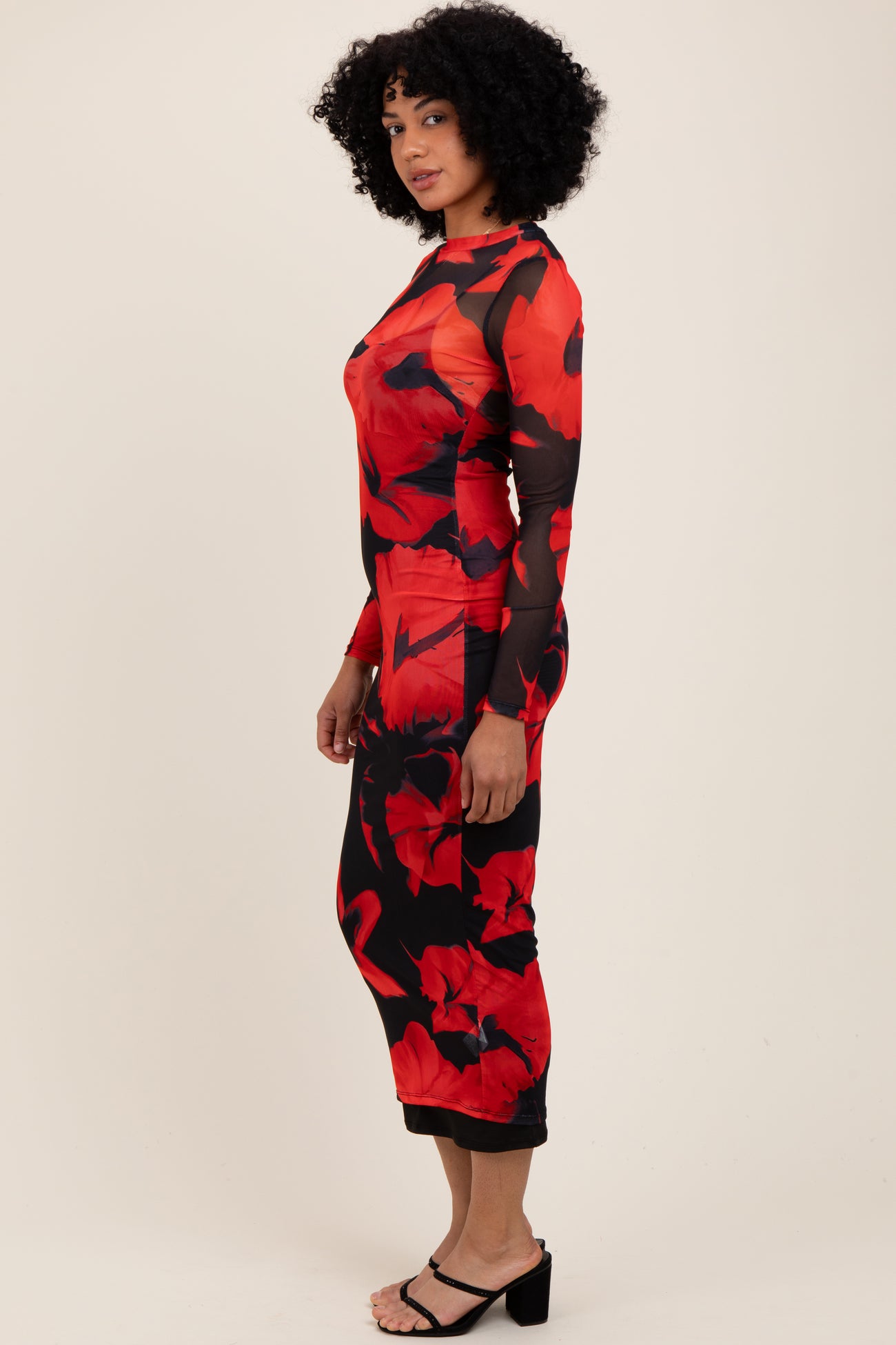 woman wearing a red floral long sleeve dress with sheer details and a fitted silhouette